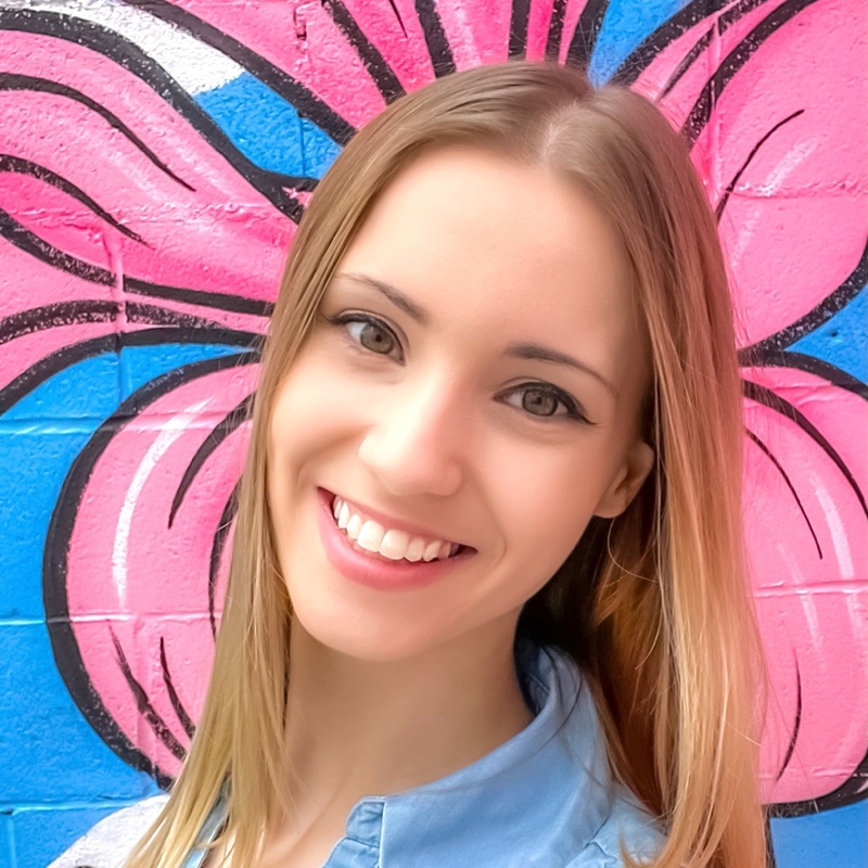 Alyssa Alexsonshk smiling in front of a pink graffiti mural