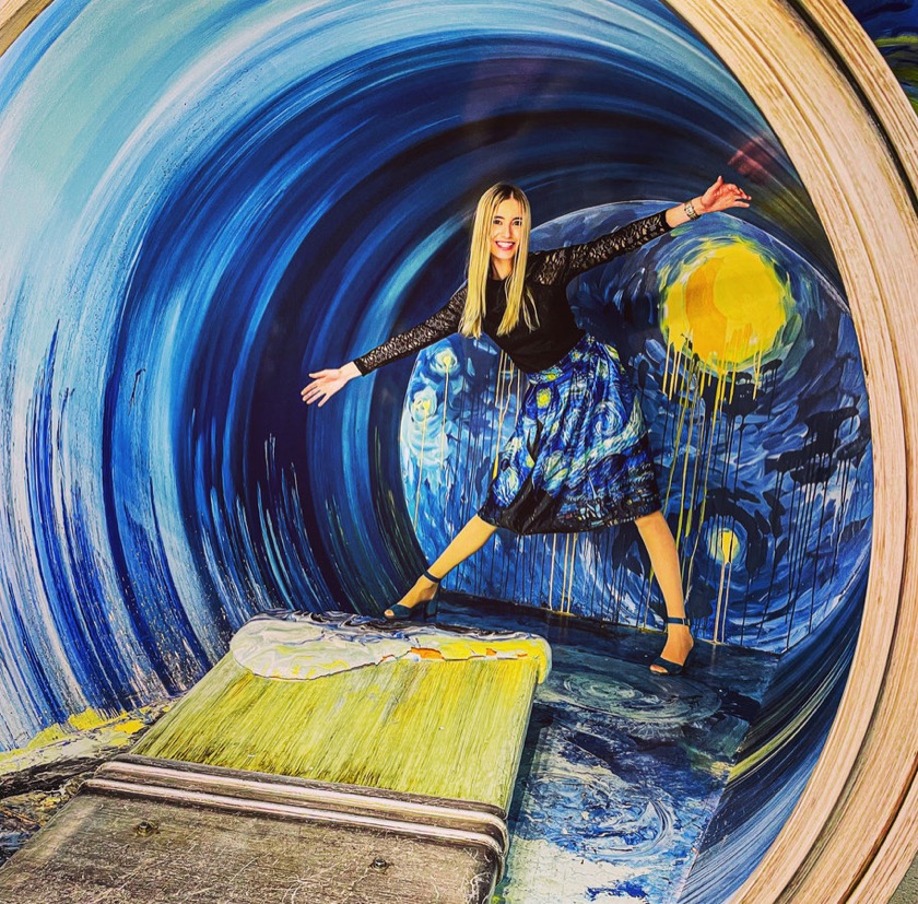 Alyssa Alexsonshk striking a playful pose inside a Van Gogh Starry Night art installation